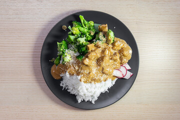 A plate of satay chicken, broccoli, and white rice.