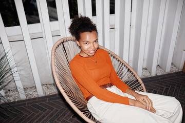 High angle portrait of young African-American girl relaxing in lounge chair a party, shot with flash