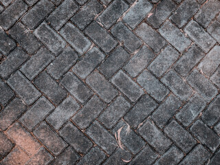 a pattern of paths in a garden arranged in bricks with dust and dry grass on them
