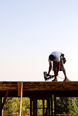 Frame carpenter using a pneumatic nail gun on a plywood deck 