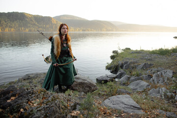 Beautiful red-haired girl-archer of Middle Ages in outdoor. Fantastic concept