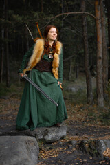 Obraz na płótnie Canvas Beautiful red-haired girl-archer of Middle Ages in outdoor. Fantastic concept