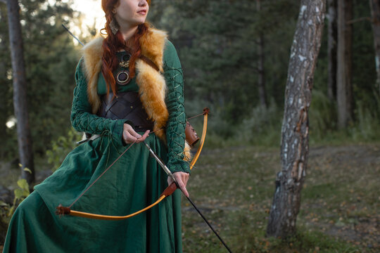 Beautiful red-haired girl-archer of Middle Ages in outdoor. Fantastic concept