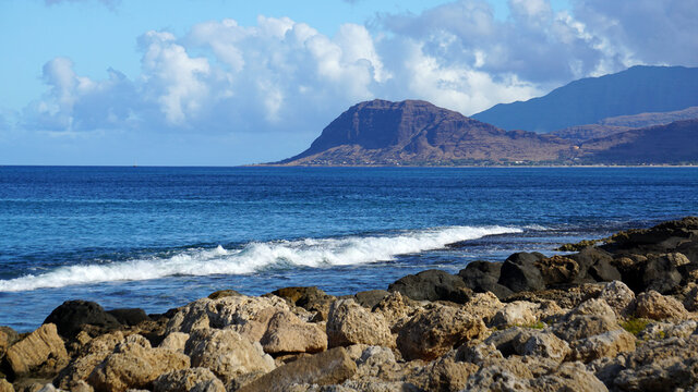 Waves roll into a lagoon on the west shore of Oahu with the Waianae Mountains in the background.