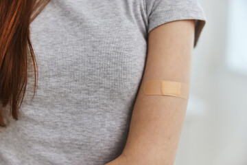 woman with adhesive plaster on shoulder vaccine passport immunity health