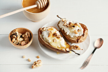 side view of halved baked pears with ricotta cheese and grilled walnuts. honey topping on dessert....