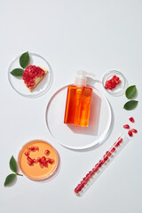 Cosmetic bottle containers with pomegranate extract top view. Close-up and white decoration background. The blank label for mock up. Glass petri dish with cosmetic products