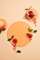 Empty background for cosmetics with pomegranate extract. Whole pomegranate and pomegranate seeds on podium circle on color background. Top view. Flat lay image. 