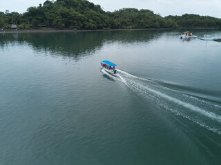 Fototapeta premium A small locally operated boat ferries locals and tourists across Cuchilla Bay to a remote part of Puntarena Province as seen from aerial drone image