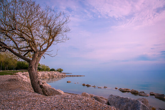 The sun sets over the main beach in Goderich, Ontario by Lake Huron, creating a beautiful magenta-tinted sky.