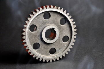 Mechanical component.   Cogwheel on a dark background. Spare parts.
