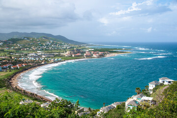 Fototapeta na wymiar The Atlantic Ocean crashes onto a sandy beach in St. Kitts on a beautiful day in this picturesque scene from the Timothy Hill Overlook.