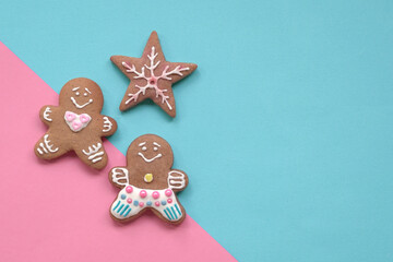 Fototapeta na wymiar Gingerbread man cookies on blue and pink background. Copy space.