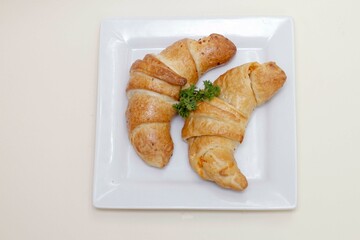 Sabrosos croissants de mantequilla servidos en un lujoso plato blanco aislado de fondo blanco.