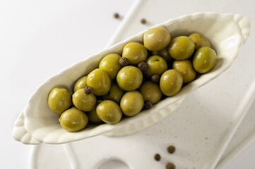 green olives in decorative dishes on a white background, top view close-up