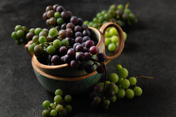 grape bunches in ceramic cups on gray background