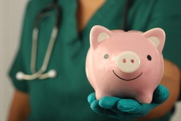 Nurse holding pink pig piggy bank