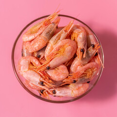 boiled shrimp in a glass bowl on a pink background, top view