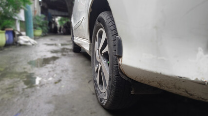 photo of the rear tire of a white car parked.