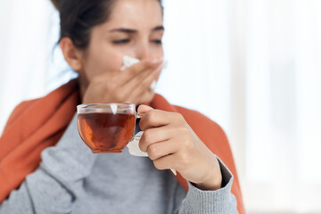 woman sitting at a table with a blanket on her shoulders treating a cold at home