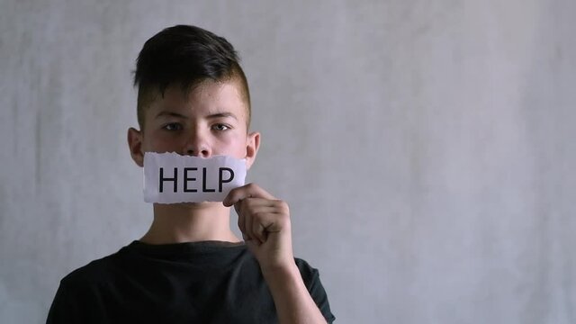 Unhappy boy shows inscription "help". Empty space for text.