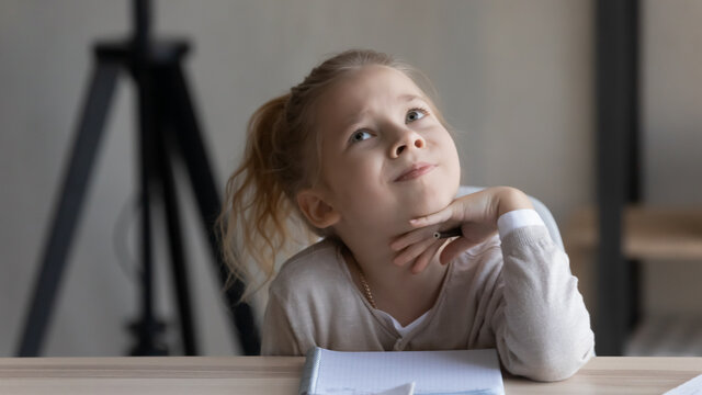 Thoughtful little kid girl looking up in distance, considering difficult school task, serious busy little female pupil studying, feeling stressed preparing assignments, homeschooling education concept