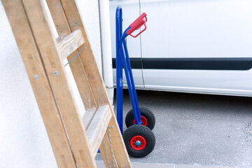 Hand truck and ladder by the wall of the house