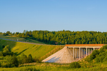 Unique concrete bridge and road against background of forest.