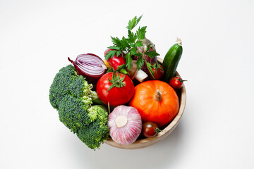 A set of fresh vegetables in a wooden bowl on a light background. View from above. Healthy food concept.