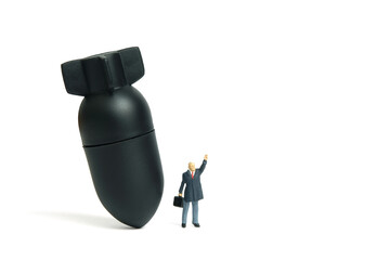 Miniature people toy figure photography. A businessman standing in front of bomb nuclear missile...