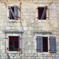 Fototapeta na wymiar Wall with opened windows of old ruined house