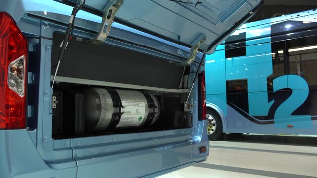 A hydrogen fuel cell buses. One bus with an open hood and a hydrogen cylinder inside.
