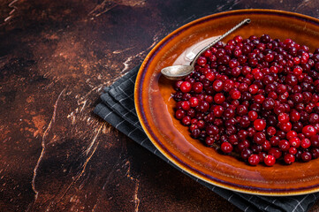 Ripe Red Cranberry berry in a rustic plate. Dark background. Top view. Copy space