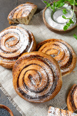 Sweet spiral bun with poppy seeds and powdered sugar large on a dark background. Delicious yeast pastries close-up. The concept of homemade high-calorie pastries	