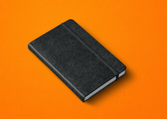 black closed notebook isolated on orange