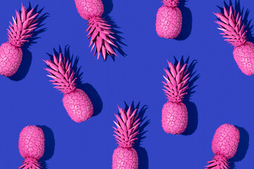 Creative pattern with bright pink painted pineapples on deep blue background. Fruit art concept. Minimal food colorful idea.