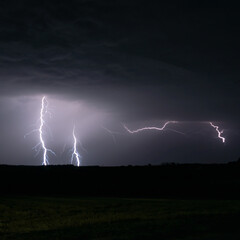 Obraz na płótnie Canvas Multiple lightning strikes lighting up the sky on a summer evening during a thunderstorm