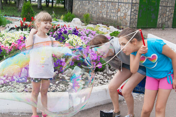 Mother with two daughters blow giant bubbles outdoor