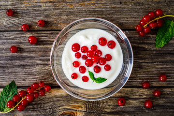 Dessert - redcurrants with yogurt on wooden table