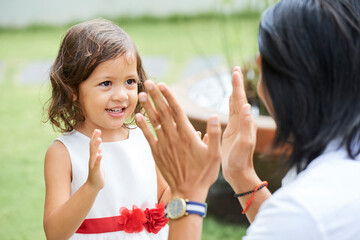 Obraz premium Adorable little girl in puffy dress clapping hands with father when they are playing outdoors