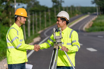 Two surveyor engineers worker handshake after making measuring with theodolite instrument equipment...