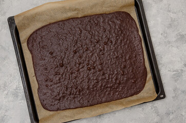 Chocolate sponge cake on a baking sheet for cooking black forest roll cake on a gray concrete...