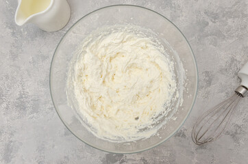Ready cream of cream cheese in a bowl to make the cake on a gray concrete background. Top view.