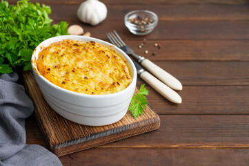 Homemade Shepherd's Pie in the casserole dish on a dark wooden background. Traditional British dish with minced meat and mashed potatoes.