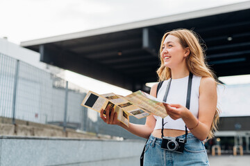 Young caucasian woman traveller holding tourist map smiling discovering and sightseeing