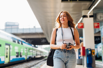 Fototapeta na wymiar Young caucasian woman tourist walking platform railway station taking photograph