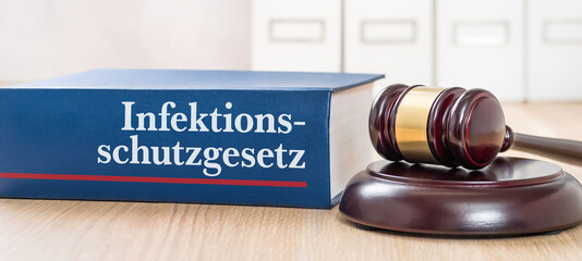 Gesetzbuch mit einem Richterhammer - InfektionsschutzgesetzGesetzbuch mit einem Richterhammer -...