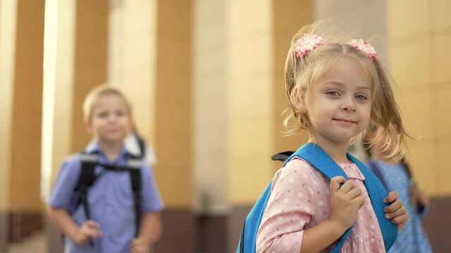 Happy girl back to school. Child goes to school with backpack. Girl with backpack walk through schoolyard. Happy family concept. Back to school. Girl walk to school with blue backpack in schoolyard