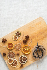 Weihnachtsschmuck getrocknete Orangenscheiben und Anis, Flatlay mit Schere Bindfaden und Holzablett