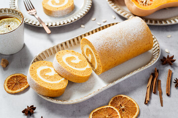 Fototapeta premium Pumpkin Cake Roll with Cream Cheese Filling. Autumn Baking. Light gray stone background.